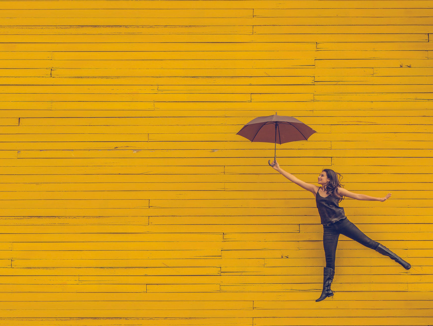 woman jumping with umbrella in hand