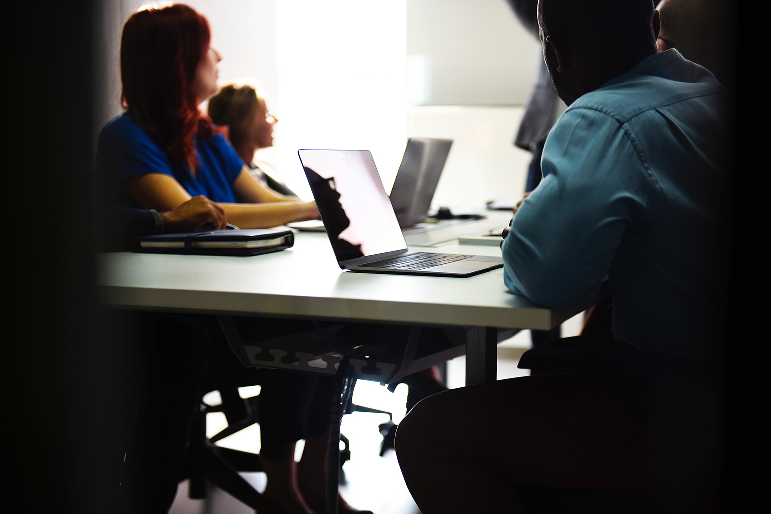 People sitting around computers at a desk.