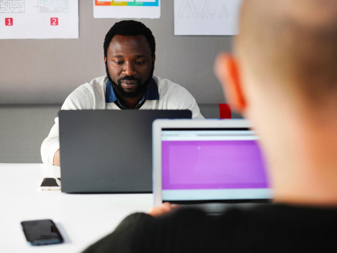 Two men on laptop facing each other