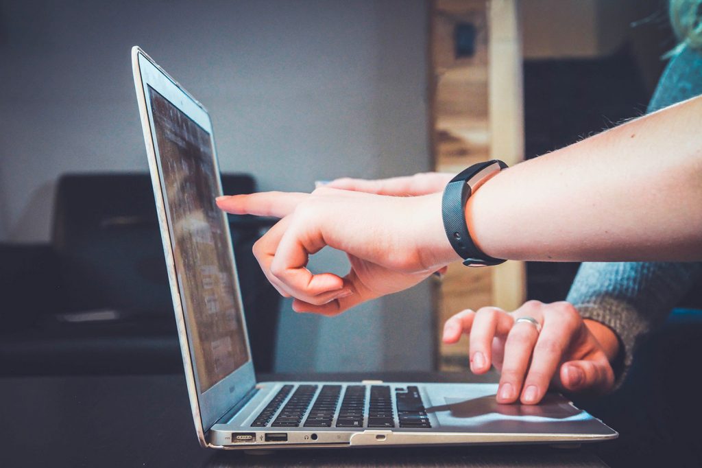 People pointing at laptop screen.