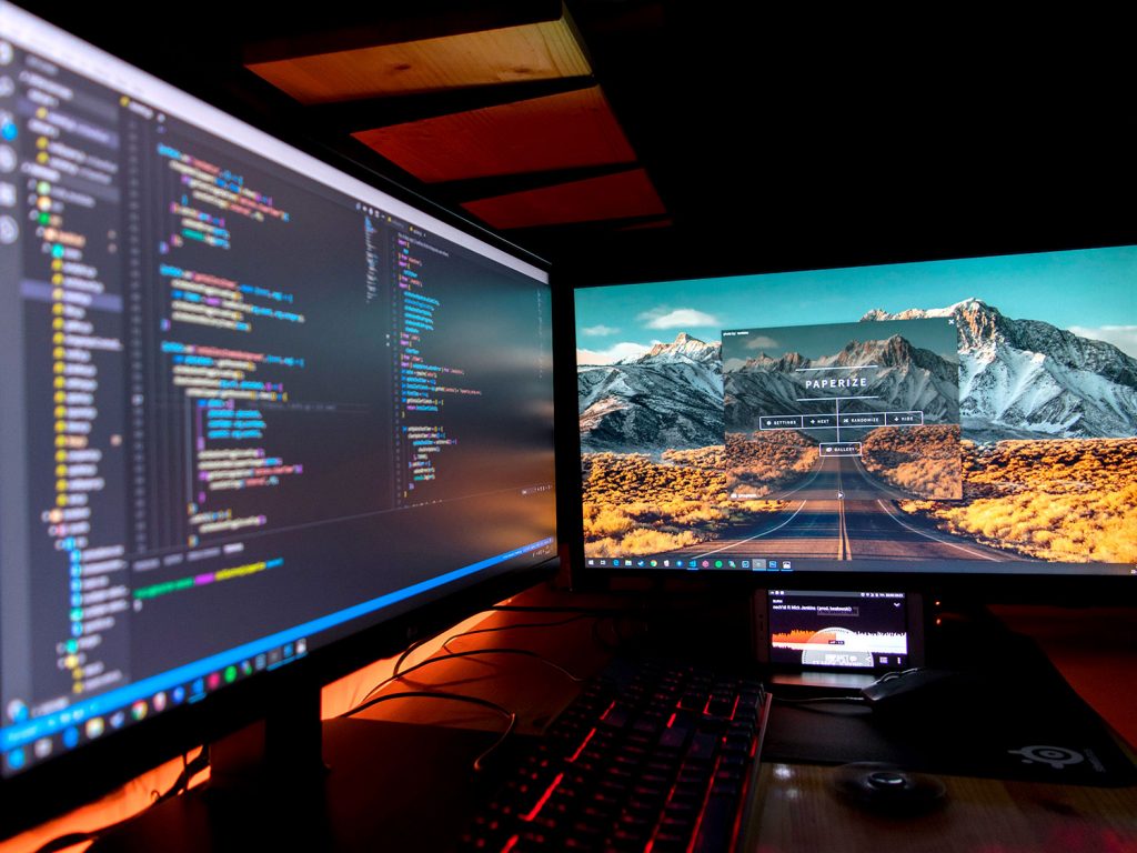 two computer screens with code and a background