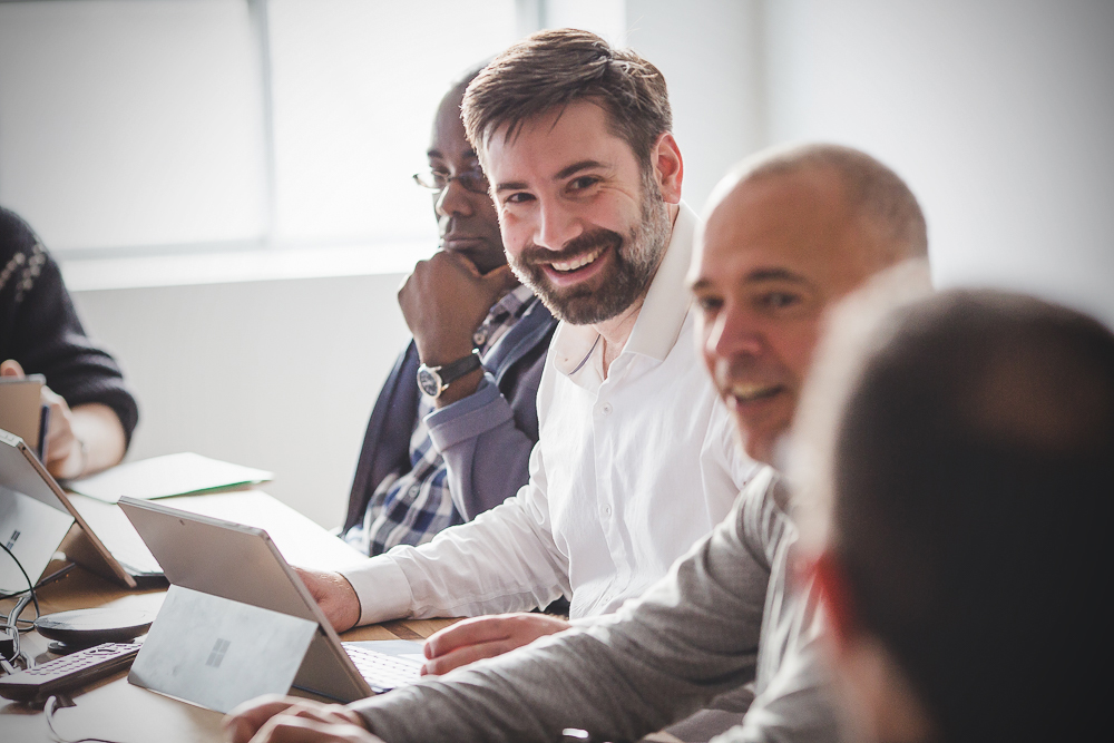 Une personne qui sourit entourée d’autres personnes au bureau